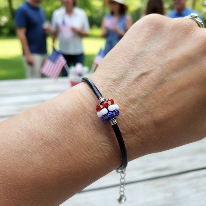 Patriotic Red White Blue Beaded Bead Leather Bracelet worn on wrist at outdoor gathering with people in background.