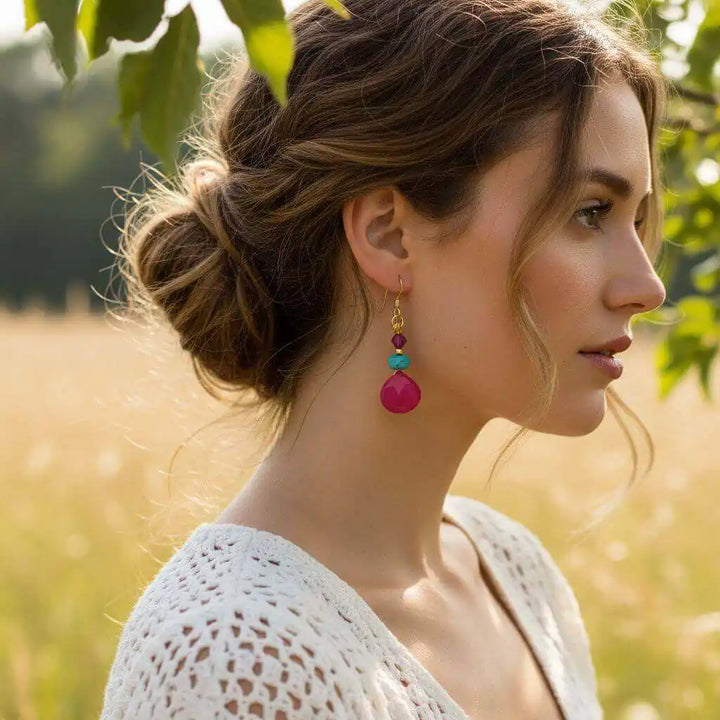 Woman wearing Gold Filled Wire Wrapped Pink And Aqua Gemstone Earrings in a field, showcasing vibrant colors and handmade elegance.