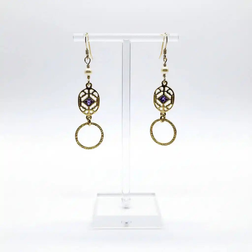 14 K Gold Filled Purple Crystal Circle Filigree Earrings displayed on a stand with intricate design and sparkling crystals.