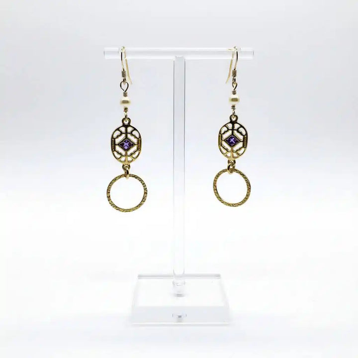 14 K Gold Filled Purple Crystal Circle Filigree Earrings displayed on a stand with intricate design and sparkling crystals.